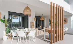 A modern interior with a dining area, seating, and a view through large windows.