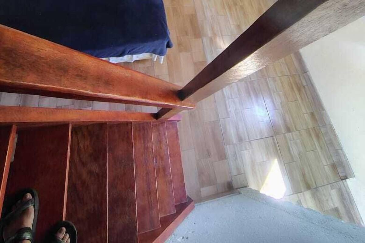 Quarto com cama, uma mesinha e uma cadeira.