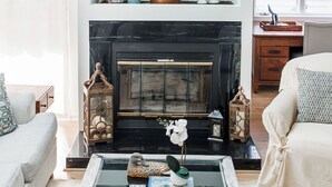 Una sala de estar moderna con chimenea, una mesa de centro con objetos decorativos y un sofá.