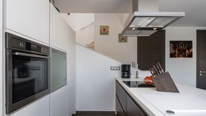 A modern kitchen with a built-in oven, a coffee maker, and a knife block on the counter. - Villa Maestral (Istria - Funtana) (Funtana)