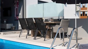 Uma área de piscina com bar, espreguiçadeiras e piscina.