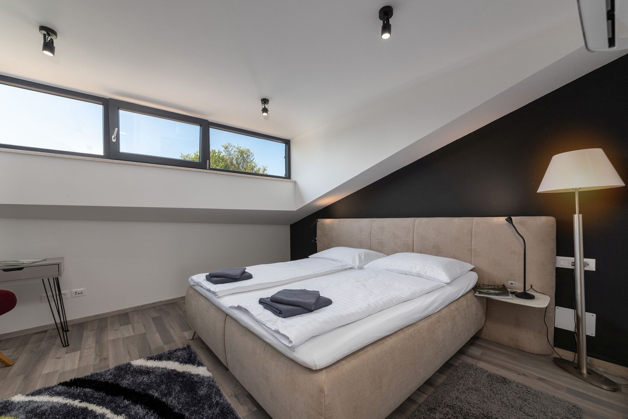 Une chambre à coucher moderne, comprenant un lit, une table de chevet, une lampe et un bureau avec une chaise.