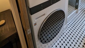 A front view of a modern LG washer and dryer unit with a control panel, located in a bathroom with a tiled floor.