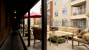 A covered outdoor seating area with wicker furniture and a red umbrella.