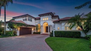 A large, two-story house with a red-tiled roof, a central archway, and a well-maintained lawn. - 944 Managed by Brampton Park (Delray Beach)
