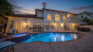 A house with a swimming pool, outdoor furniture, and a well-lit patio area.