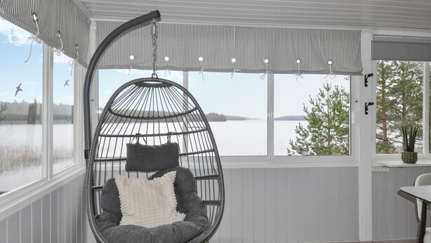 A room with a large window overlooking a lake, a hanging chair with cushions, and a potted plant on a windowsill. - Gorgeous home in Vretstorp (Vretstorp)