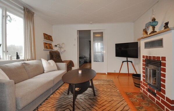 A living room with a sofa, a coffee table, a fireplace, and a television.