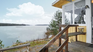 A wooden deck leading to a cabin with a large window overlooking a calm lake. - Gorgeous home in Vretstorp (Vretstorp)