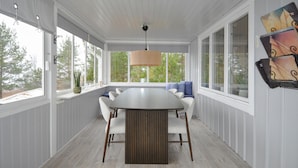 A covered dining area with a large table and chairs, large windows, and a hanging light fixture. - Gorgeous home in Vretstorp (Vretstorp)