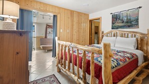 Une chambre à coucher avec un cadre de lit en bois, une couvre-lit matelassée et un tableau accroché au mur.