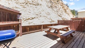 Une terrasse en bois avec des tables de pique-nique et un barbecue.