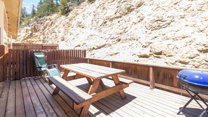 Une terrasse en bois avec des tables de pique-nique et un barbecue.