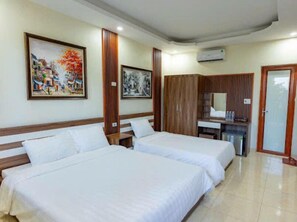 Habitación de hotel con dos camas, un escritorio, un armario y dos cuadros en la pared.