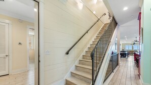Eine Treppe mit Holzverkleidung und Metallgeländern, die zu einem Raum mit Holzboden und einer Tür links führt.