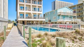 Ein Strandhotel mit Pool, mehreren Balkonen und einer Holzpromenade.
