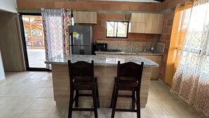 A spacious kitchen with a central island, wooden cabinets, and a view through a window.