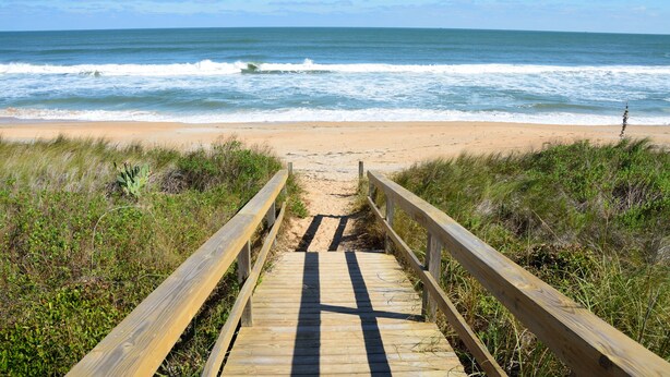 A wooden boardwalk leading to a beach with waves in the background. - Charming Sandcastles Condo – Steps to the Beach w/ Pool, Hot Tub & Tennis! (Cocoa Beach)
