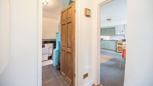A hallway leading to a bathroom with a blue towel rack and a wooden door. - 2 Lion Cottages, Knodishall (Knodishall)