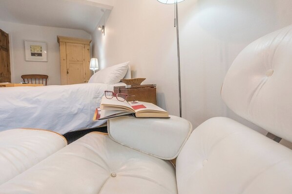 A bedroom with a bed, a nightstand, a lamp, and a chair with a book and glasses on it. - 2 Lion Cottages, Knodishall (Knodishall)