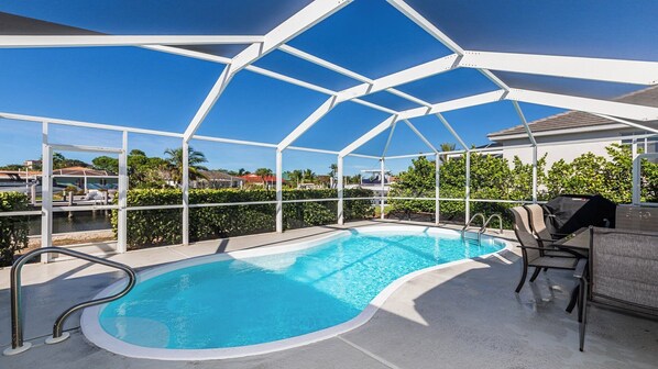 A covered outdoor swimming pool with a view of the surrounding area, including a body of water and greenery.