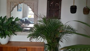 Una habitación con un espejo grande y ornamentado, un aparador de madera y varias plantas en macetas.