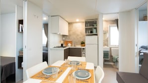 A compact living space with a dining area, kitchenette, and a small bedroom.