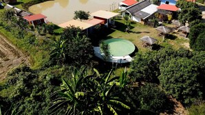 An aerial view of a rural property with a large pond, several houses, and a swimming pool.
