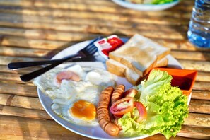 En tallrik med ägg, korv, sallad och rostat bröd på ett träbord.