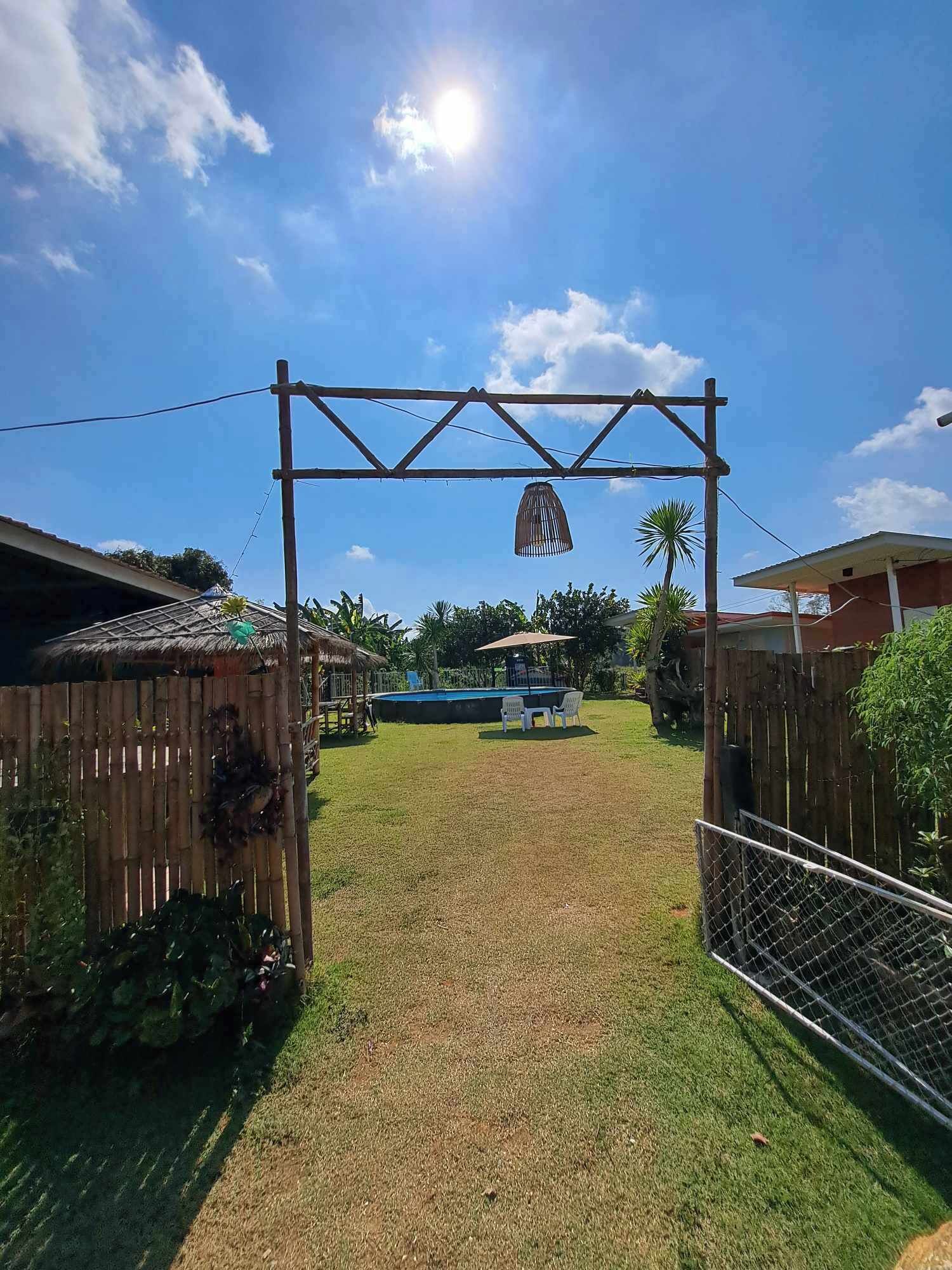 A backyard with a pool, a wooden fence, and a hanging light fixture.