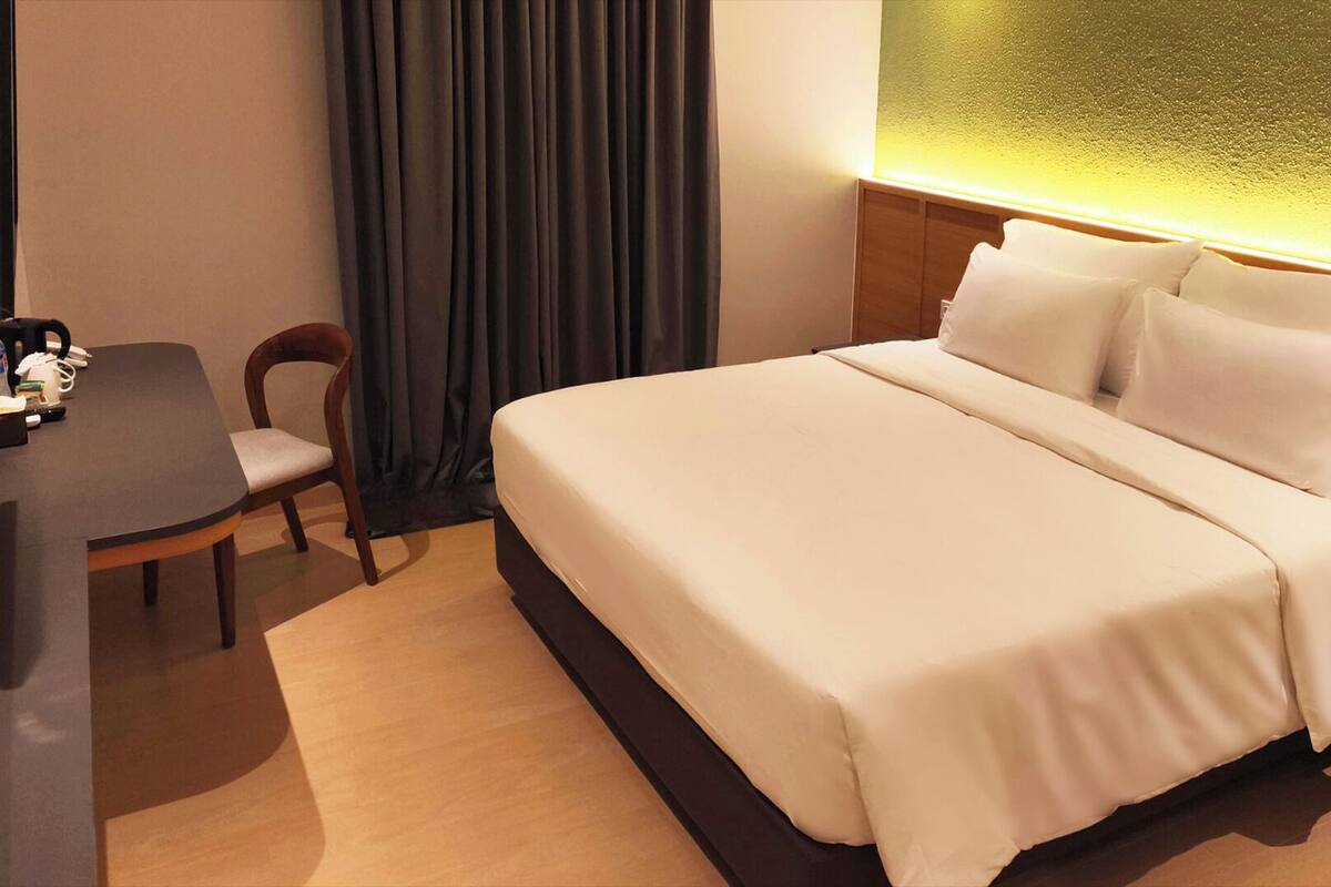 A hotel room with a bed, bedside tables, a desk, and a chair.