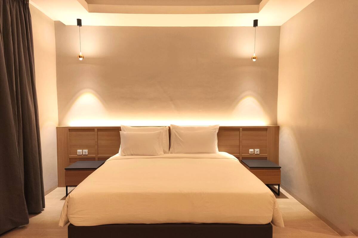 A modern bedroom with a large bed, two bedside tables, and a ceiling light fixture.