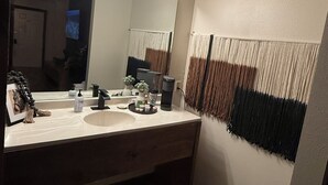 A bathroom with a large mirror, vanity, and a lighted vanity area.