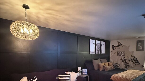 A modern living room with a dark-colored sofa, a wooden coffee table, and a hanging light fixture.