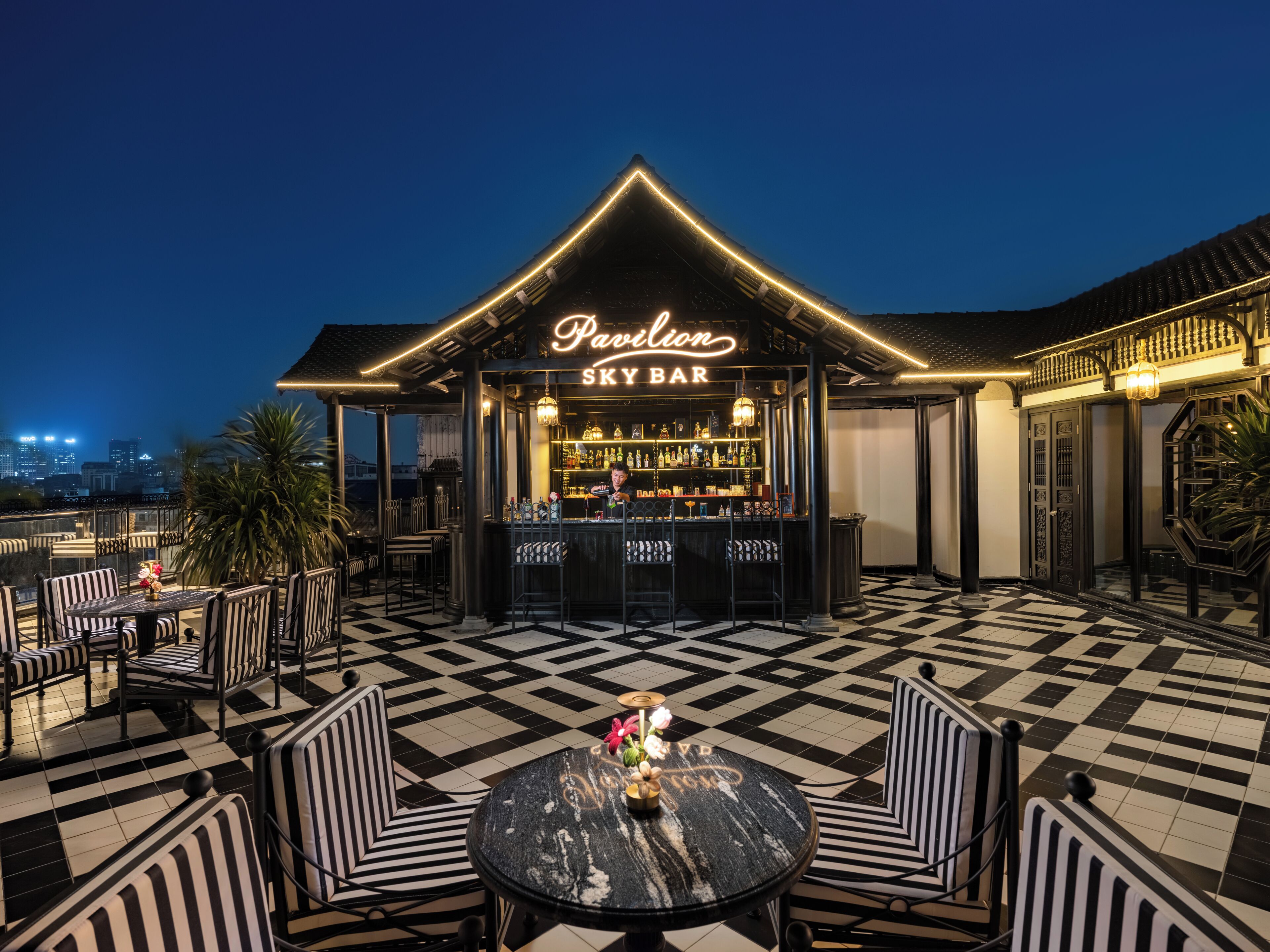 A rooftop bar with a checkered floor, bar counter, and seating area.
