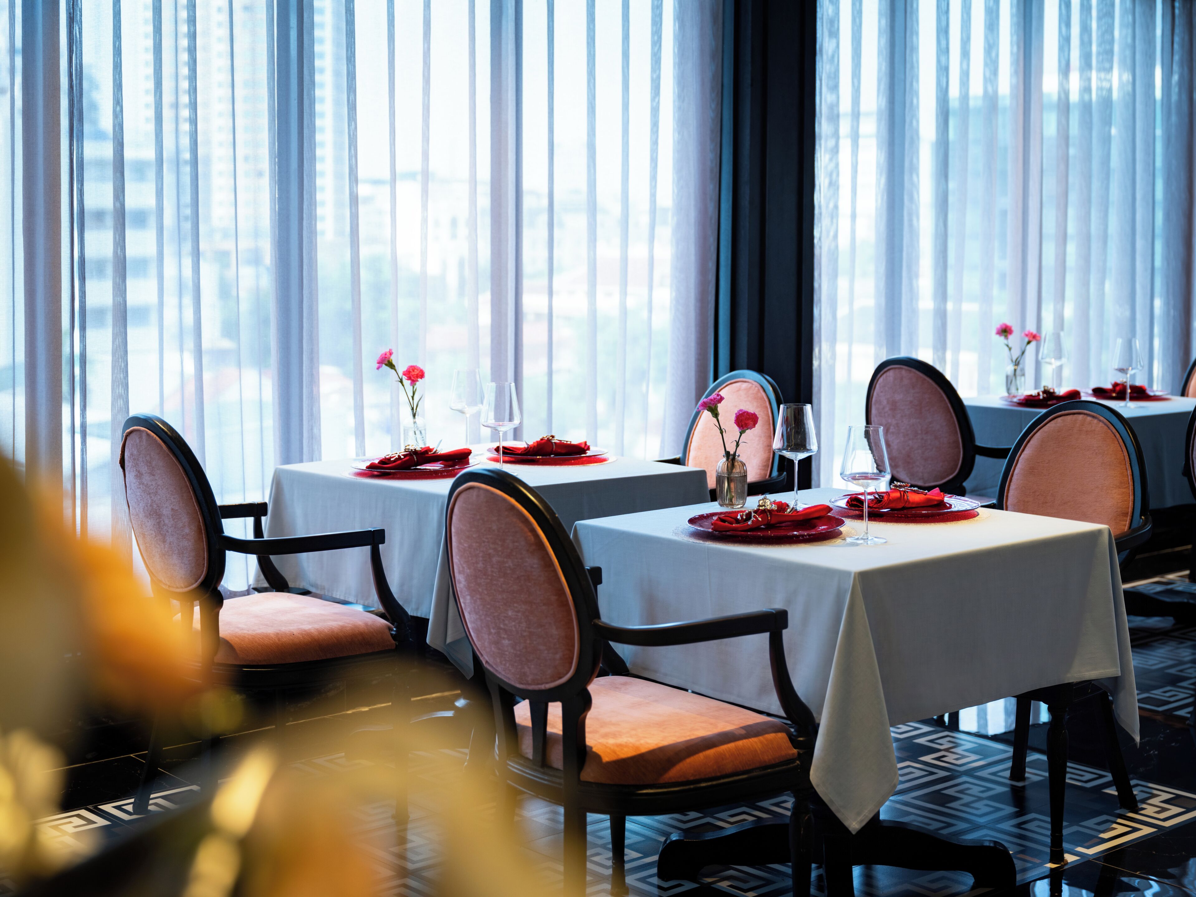 Un restaurante con mesas dispuestas para comer, sillas y vistas amplias a través de grandes ventanales.