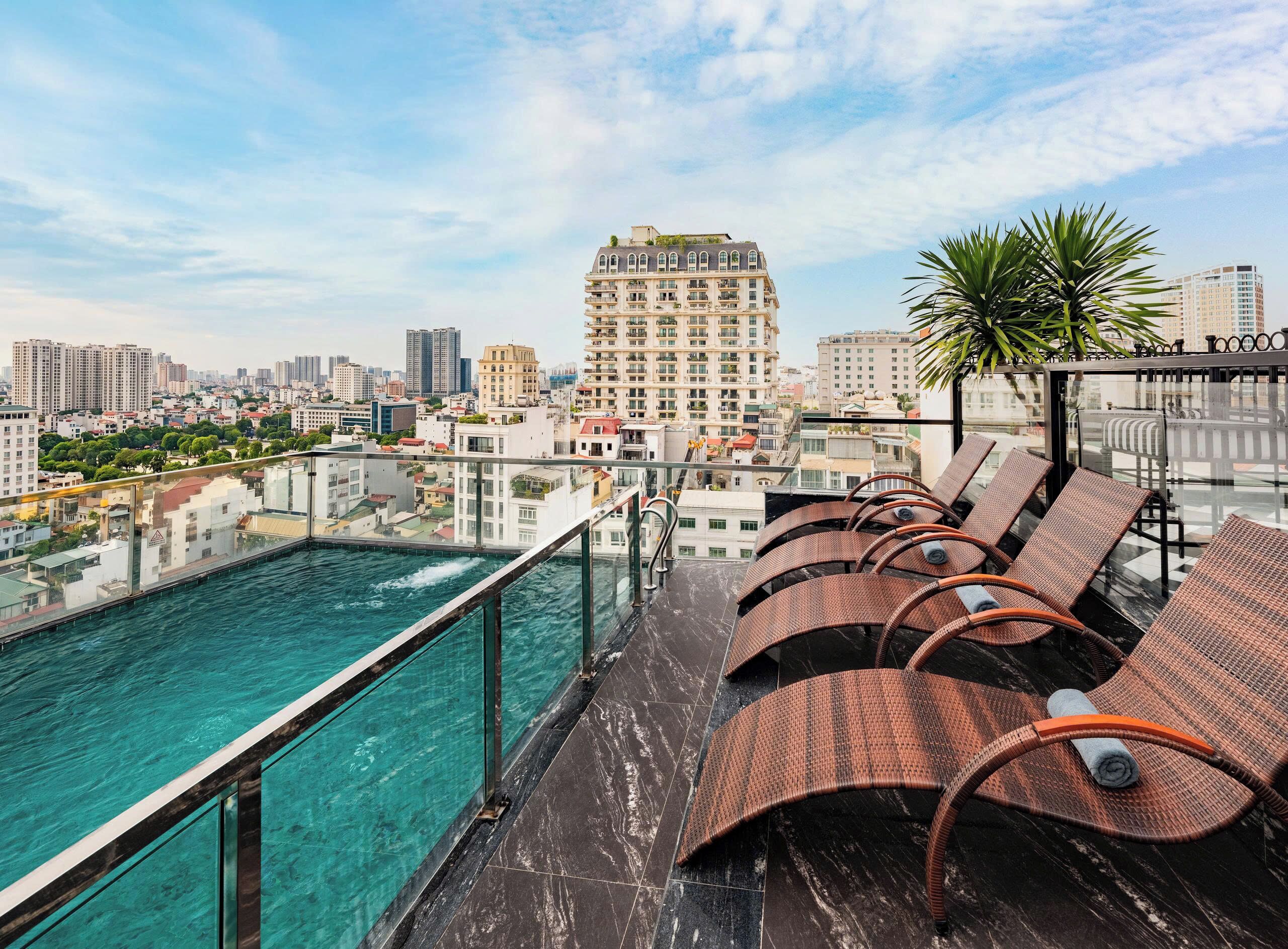 A rooftop pool area with lounge chairs and a cityscape view.