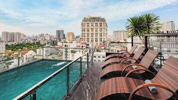 A rooftop pool area with lounge chairs and a cityscape view.