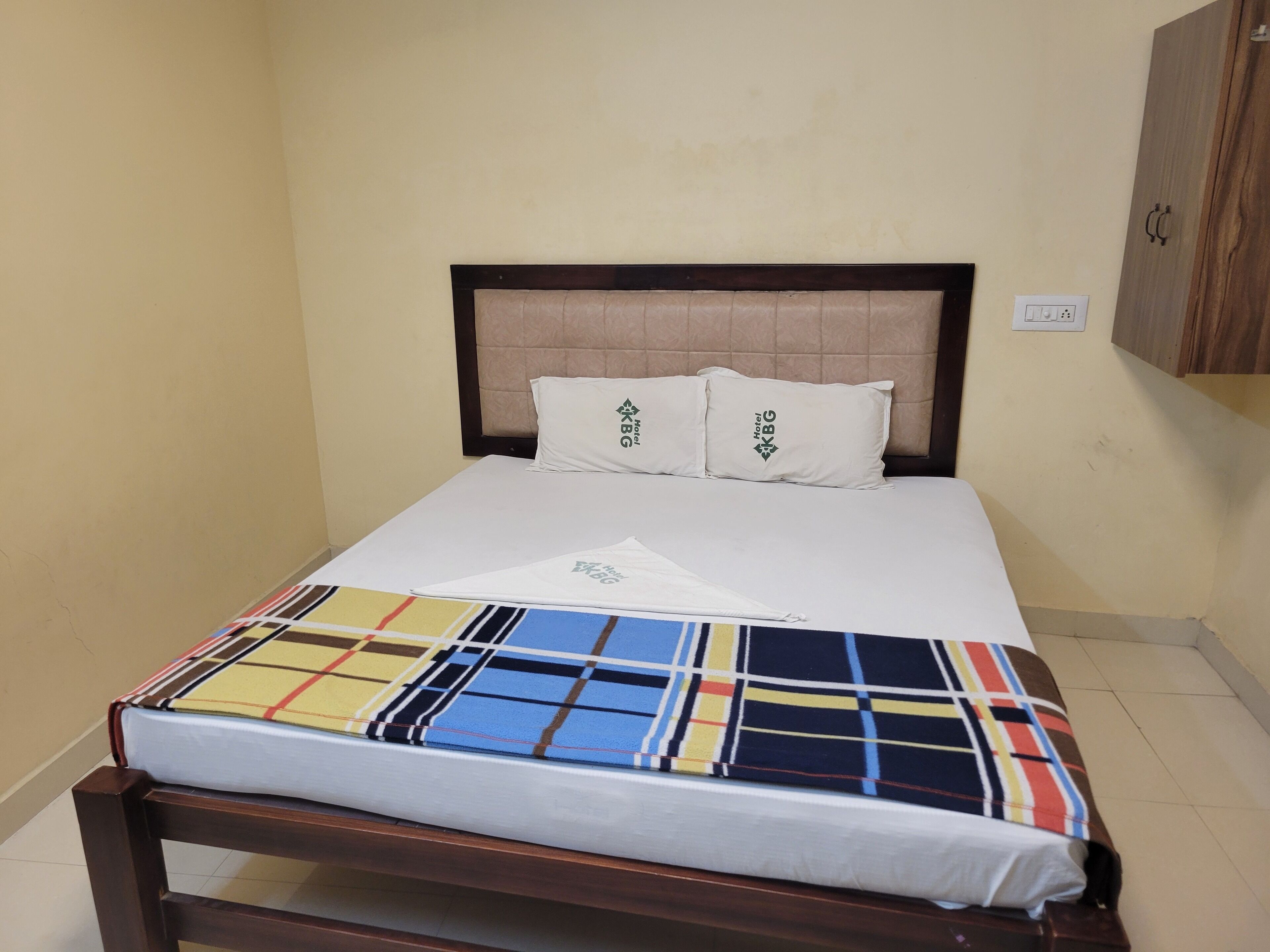 A single bed with a wooden frame, a headboard, and two pillows with a logo.