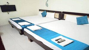 Een hotelkamer met twee eenpersoonsbedden, elk met een blauwe sprei en witte kussens. Er is een flatscreen televisie aan de muur boven de bedden bevestigd.
