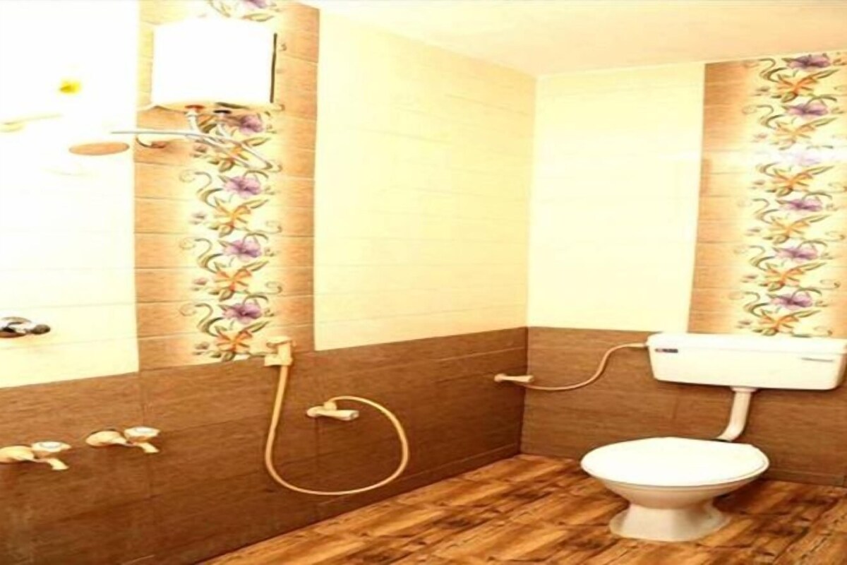 Une salle de bain avec un plancher en bois, des toilettes et un espace douche.