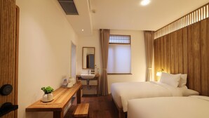 A hotel room with two beds, a wooden desk with a plant, a sink, and a mirror. - Hantanginn Hotel (Xi'an)