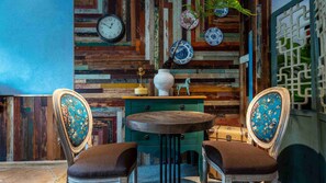 Una habitación con pared de madera rústica, una mesa redonda, dos sillas y un reloj.
