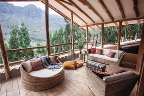 A cozy, rustic room with a large window offering a mountain view, wooden furniture, and a woven bench. - Samay Wasi Mala (Mala)
