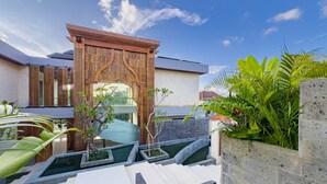 A modern building with a decorative entrance, a pool area with steps, and lush greenery. - Narawangsa Villa | 4br | Rooftop West Coast View (Kerobokan)