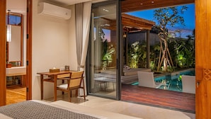 A bedroom with a large bed, a desk, and a view of an outdoor pool area. - Narawangsa Villa | 4br | Rooftop West Coast View (Kerobokan)