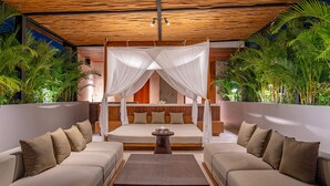 A room with a bed, a sofa, a coffee table, and a canopy bed. - Narawangsa Villa | 4br | Rooftop West Coast View (Kerobokan)