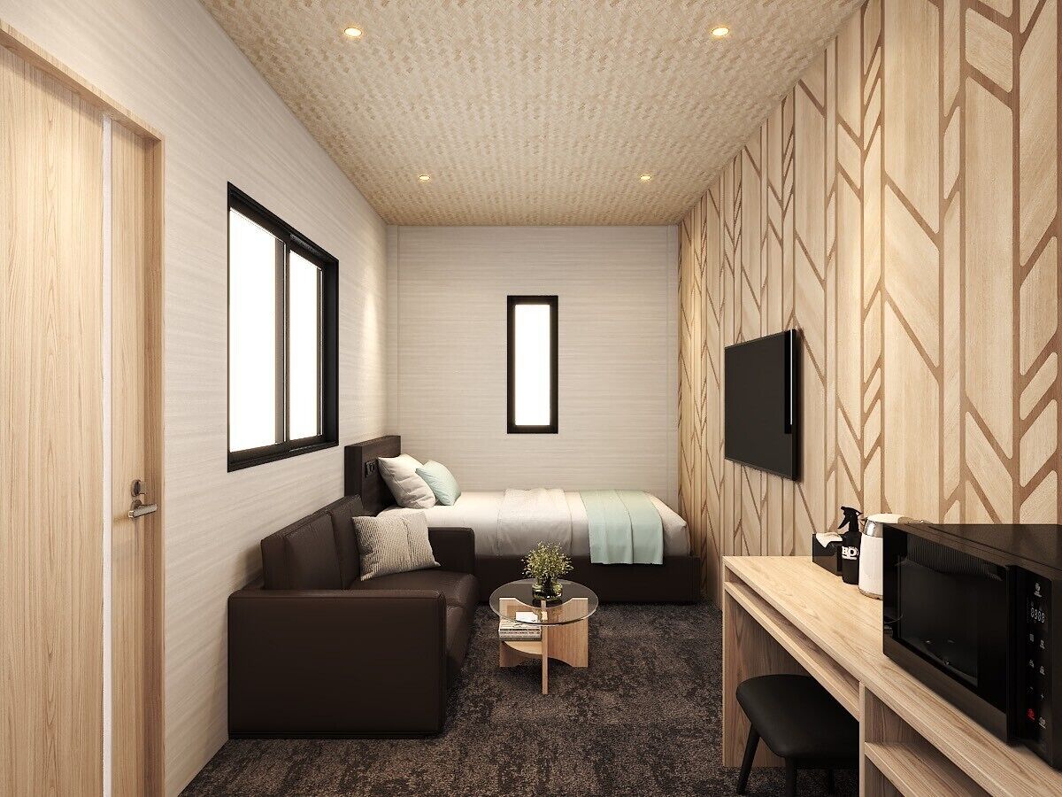 A modern bedroom with a bed, a sofa, a desk, and a television.