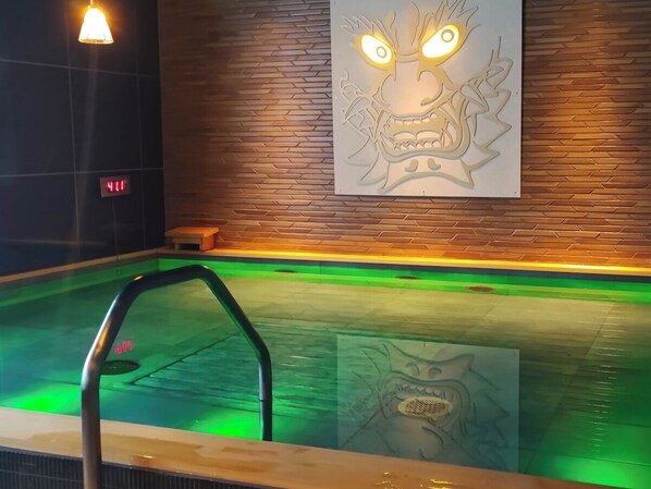 A swimming pool with a metal ladder, a digital clock, and a wall with a dragon mural.