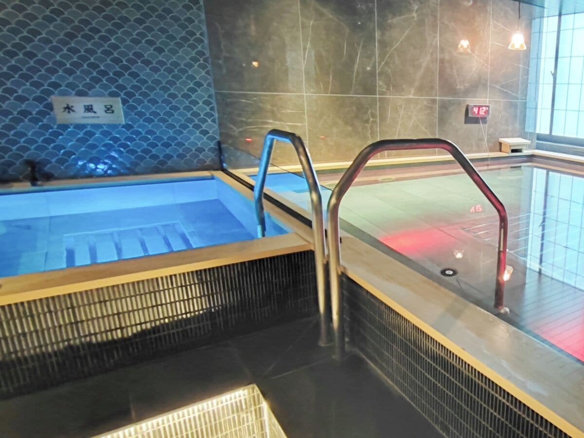 Un espace de détente avec un jacuzzi, des garde-corps en métal et un mur carrelé.